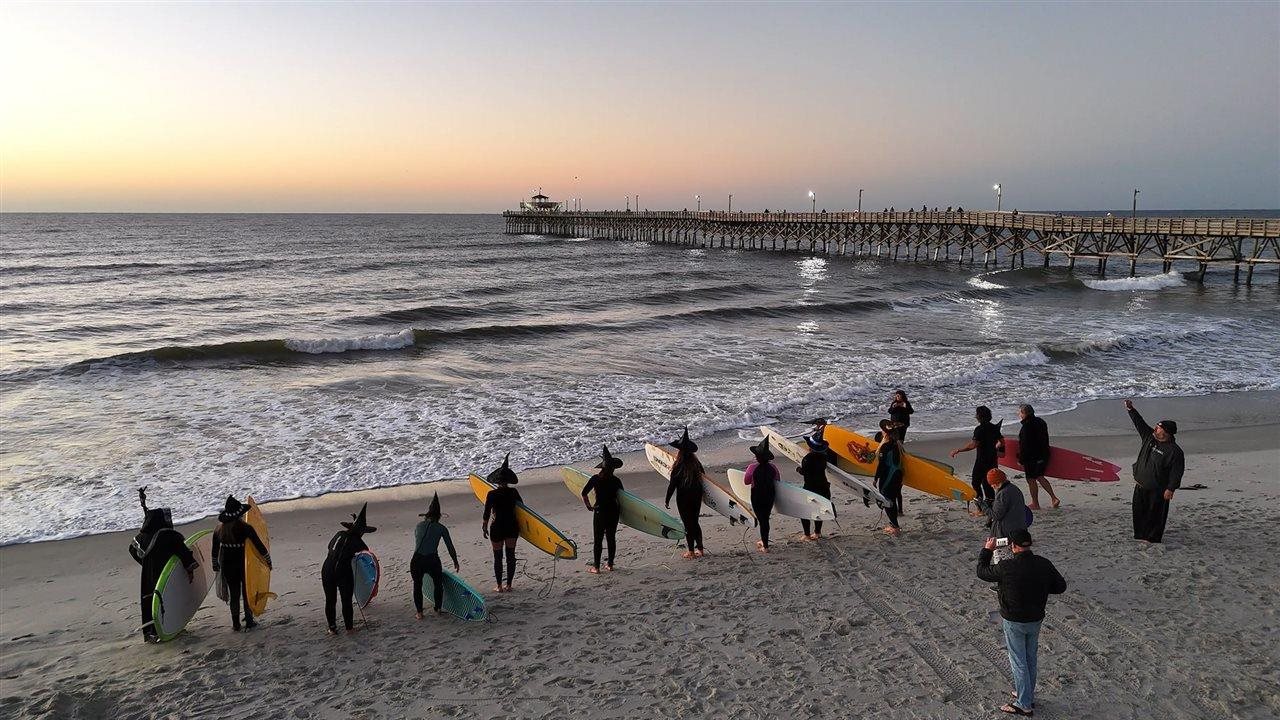 People in witch hats at Myrtle Beach preparing to surf.