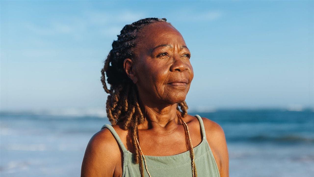 Senior woman standing on a beach near the ocean. MCED testing can detect signals of cancer in the body and provide insight before symptoms even appear.