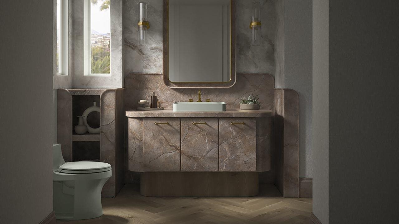 Soft pink faux marble cabinetry with gold tone fixtures in powder room.