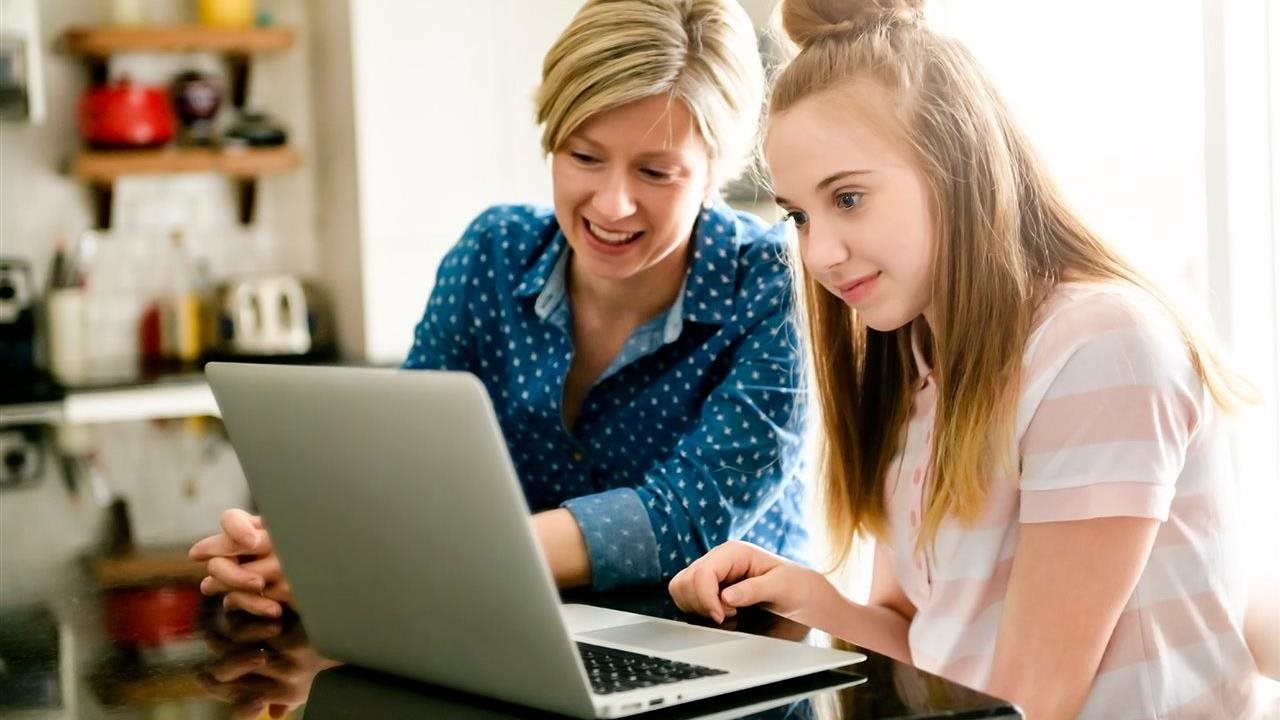 Mother and daughter on laptop in the kitchen, leaning about Pearson's Connections Academy AI policy for responsible AI use to help her child become a confident, adaptable, lifelong learner.