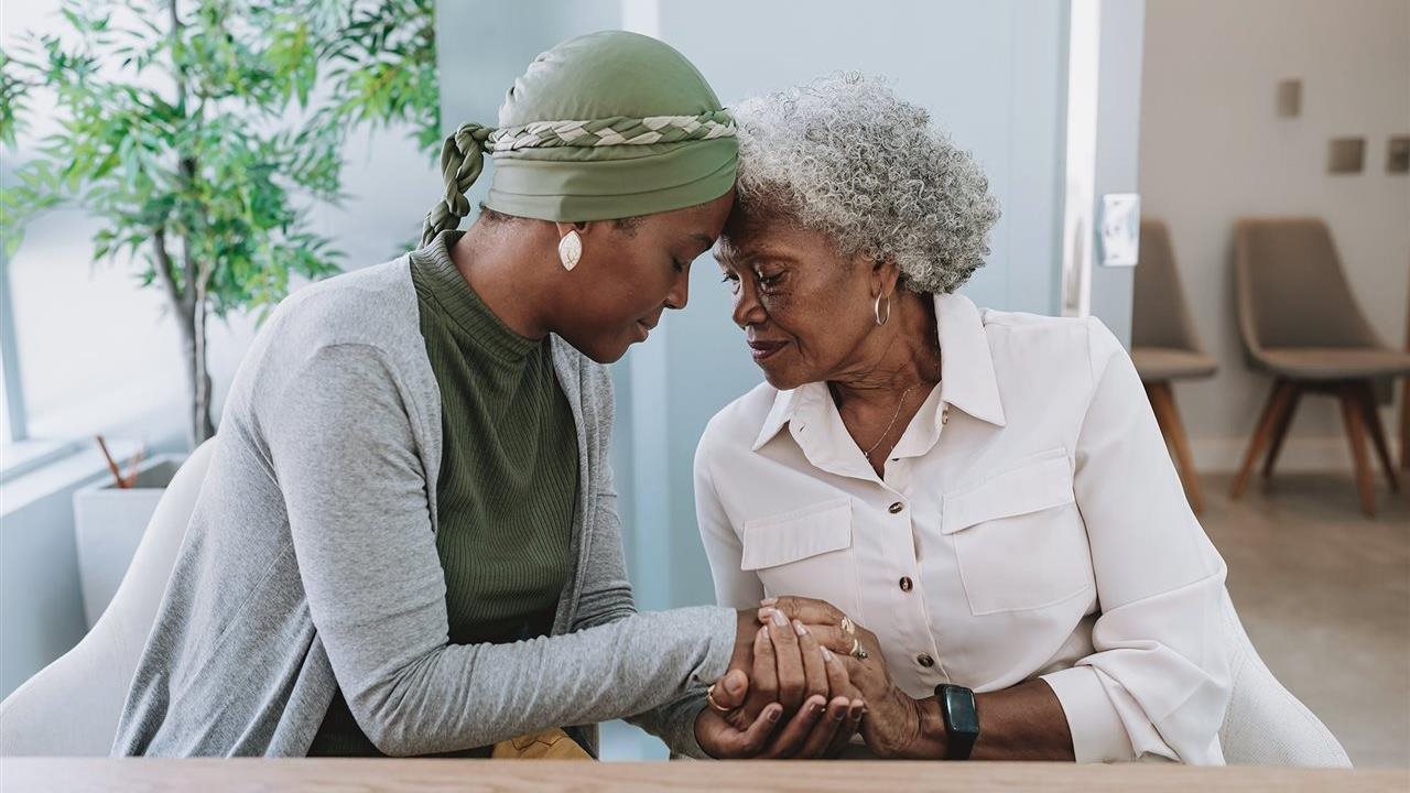 Hija consolando a su madre anciana. Investigadores de Bristol Myers Squibb están realizando ensayos clínicos para la enfermedad de Alzheimer.