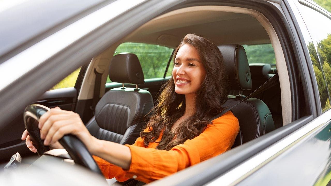 Smiling woman enjoying driving her car.