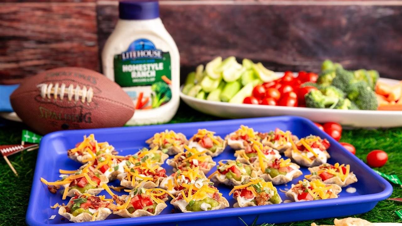 A game day appetizer Guacamole bites on a tray with a football, a plate of vegetables and a bottle of Litehouse Homestyle Ranch Dressing & Dip  in the background.