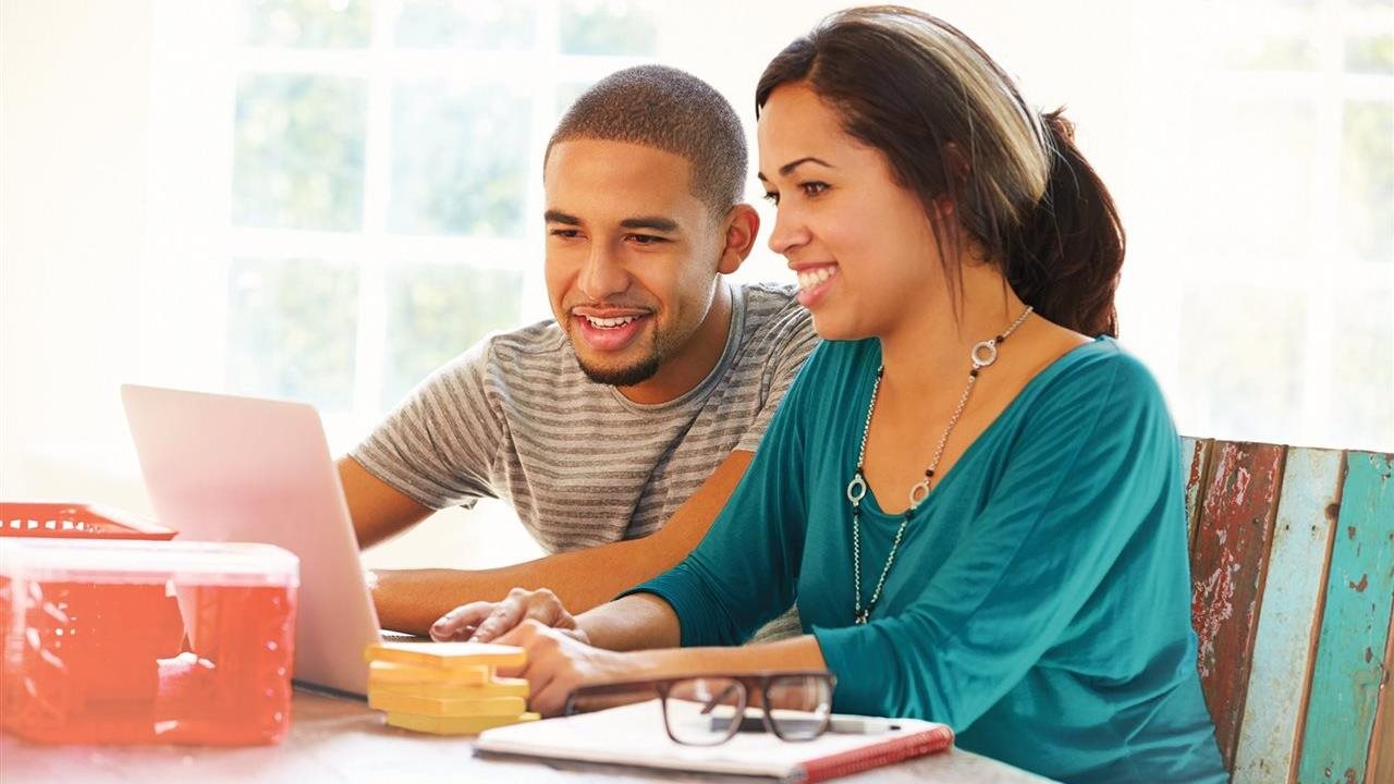 Couple at their laptop, comparing HVAC systems online. while sitting in the kitchen.