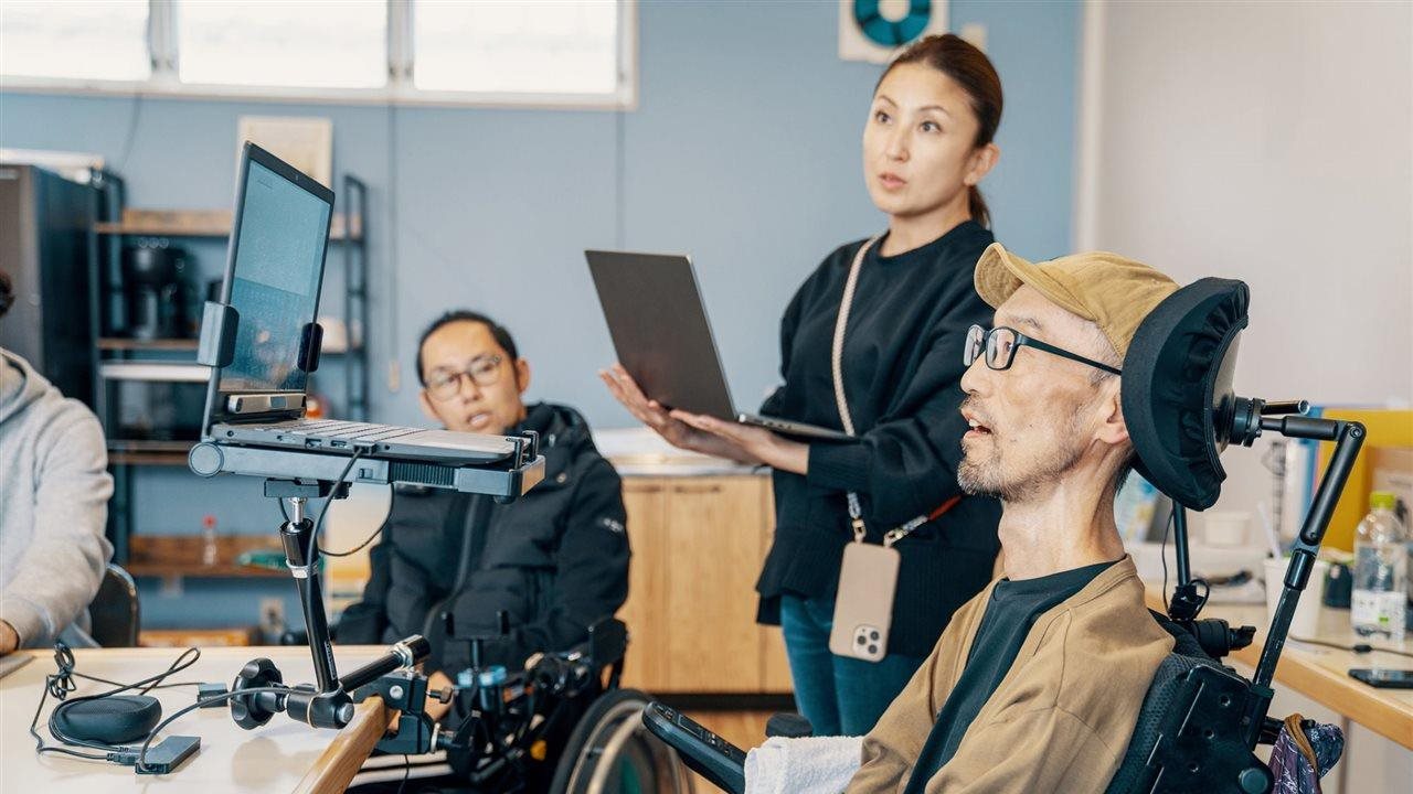 Woman teaching a class of workers with disabilities to use computers.