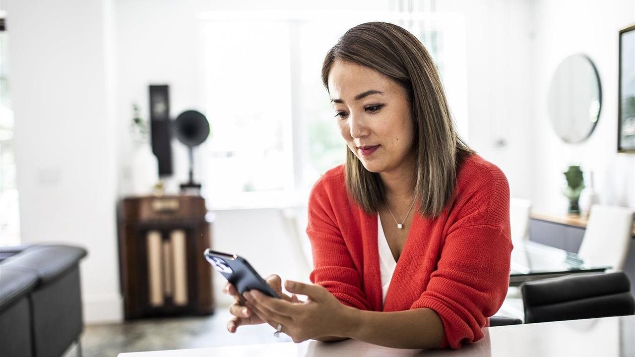 Woman using a phone app at home. With the Sydney Health app, members can find in-network care, see estimated costs and manage benefits in one place.