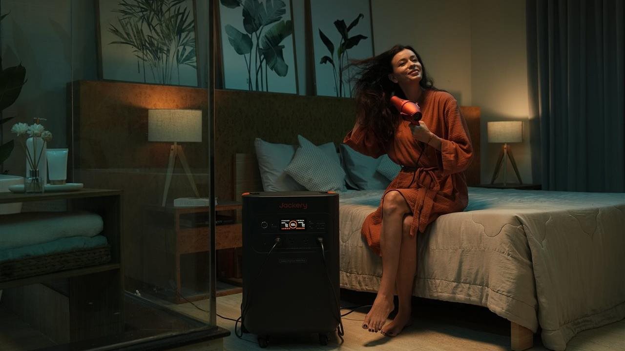Woman blow-drying her hair using power from the Jackery Solar generator 5000 plus.
