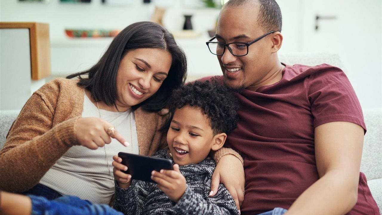 A couple and son using a cell phone at home. Medicaid covers a wide range of families and individuals.