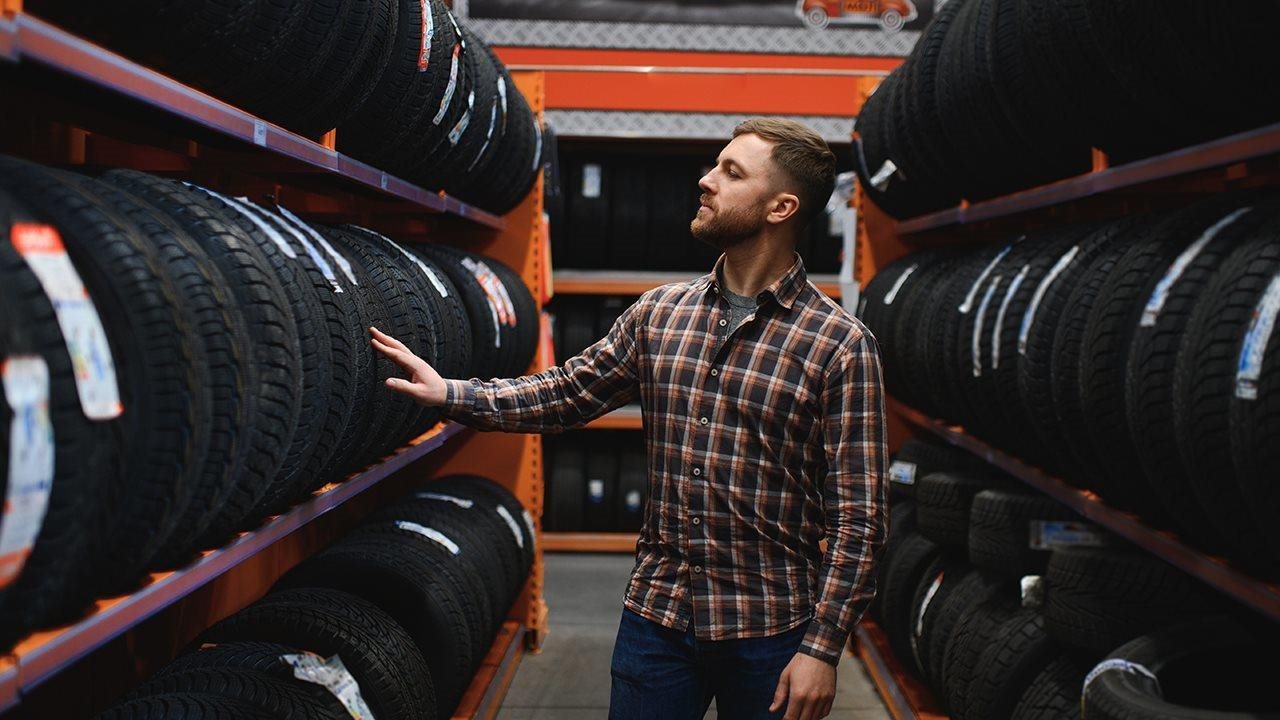 Man looking at rows and rows of tires in a tire store.