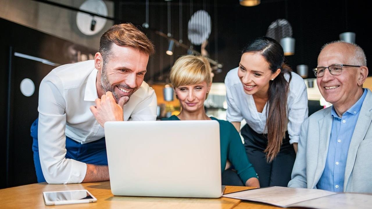 A group of four people work at the same laptop. See how whole-company AI certification works at www.certifiedai360.com.