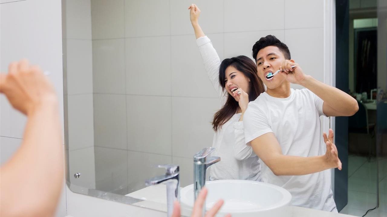Couple singing while brushing their teeth and listening to music in the bathroom