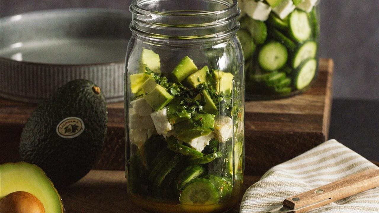 California Avocado Cucumber Salad with Feta in a jar on counter next to California Avocados on kitchen counter top.