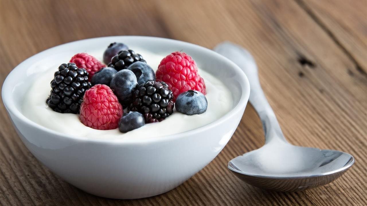 Bowl of fresh mixed raspberries, blackberries and blueberries with yogurt as recommended by the Director of Nutrition & Scientific Affairs at Danone North America.