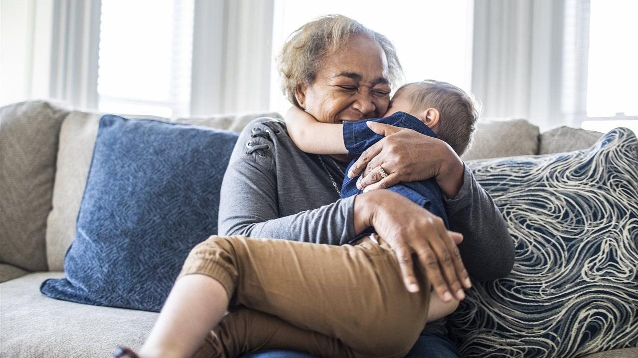 La abuela abraza a su nieto mientras están sentados en el sofá. UnitedHealthCare-UHC alienta a las familias a celebrar a los abuelos.