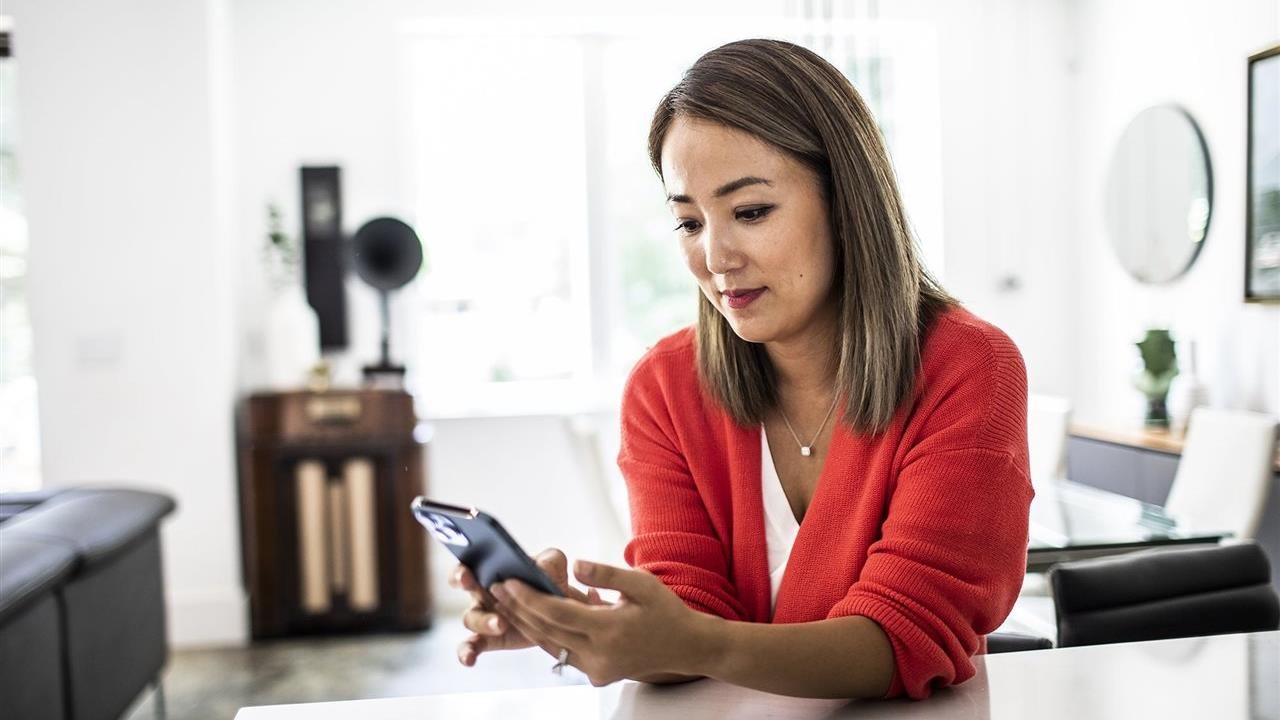 Woman using a phone app at home. With the Sydney Health app, members can find in-network care, see estimated costs and manage benefits in one place.