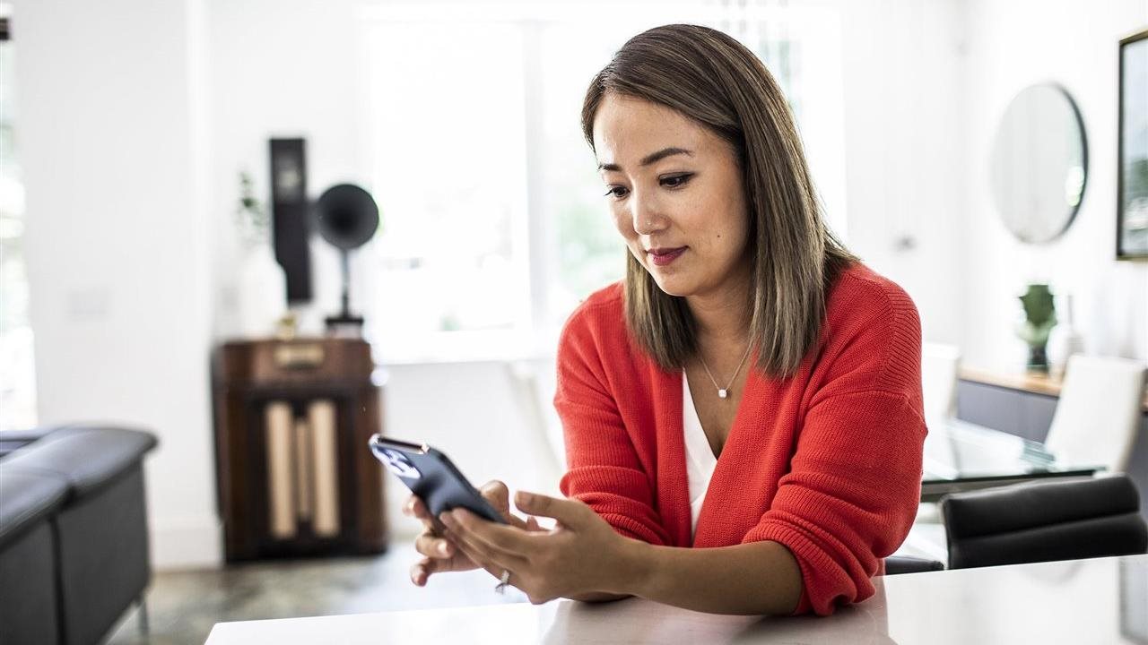 Woman using a phone app at home. With the Sydney Health app, members can find in-network care, see estimated costs and manage benefits in one place.