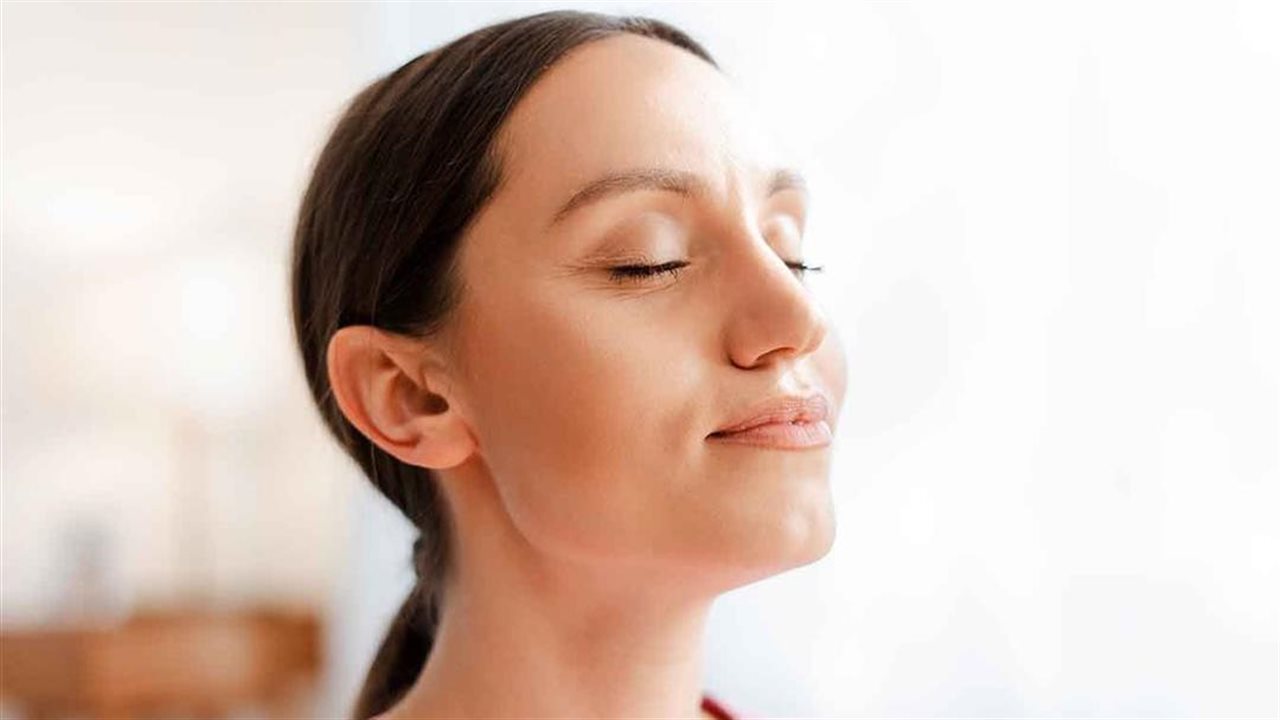 Mujer con los ojos cerrados respirando profundamente tras haber sentido alivio de sus síntomas de alergia y asma.