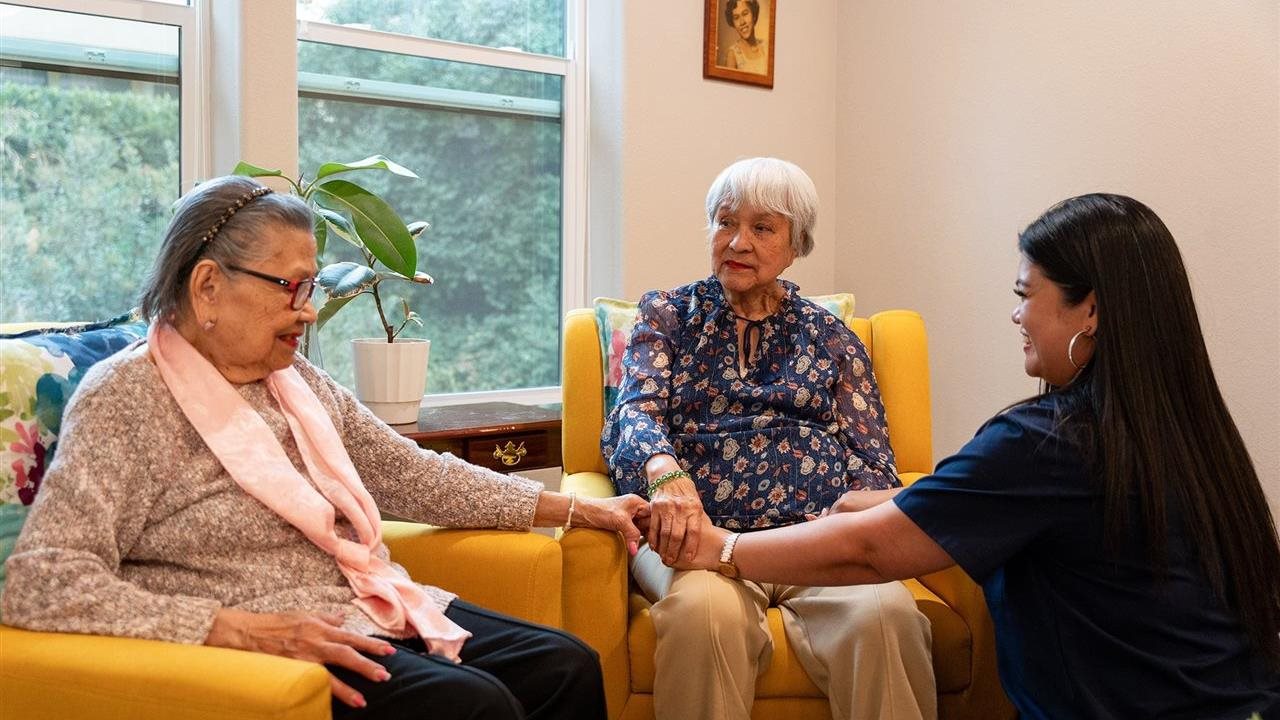 Strela's mother and grandmother holding hands with a provider at Vivid Life Home Care.