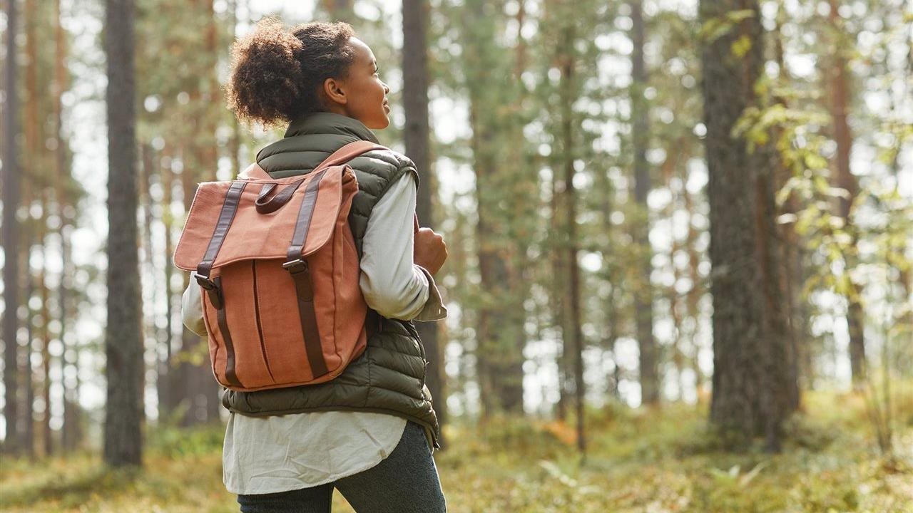 Woman hiking in the woods. Tom's of Maine, with its Stewardship Model, evalulates ingredients, where they come from and how they get them.