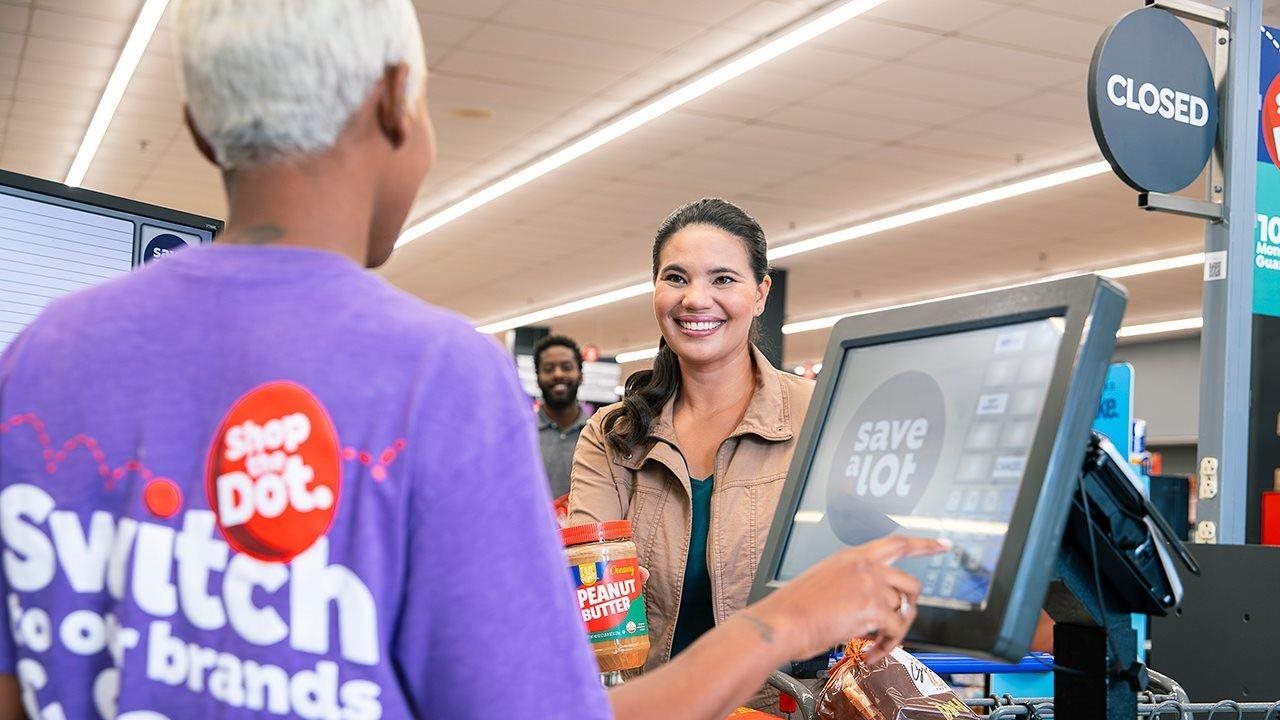 A checker helping a customer check out at a Save A Lot store.
