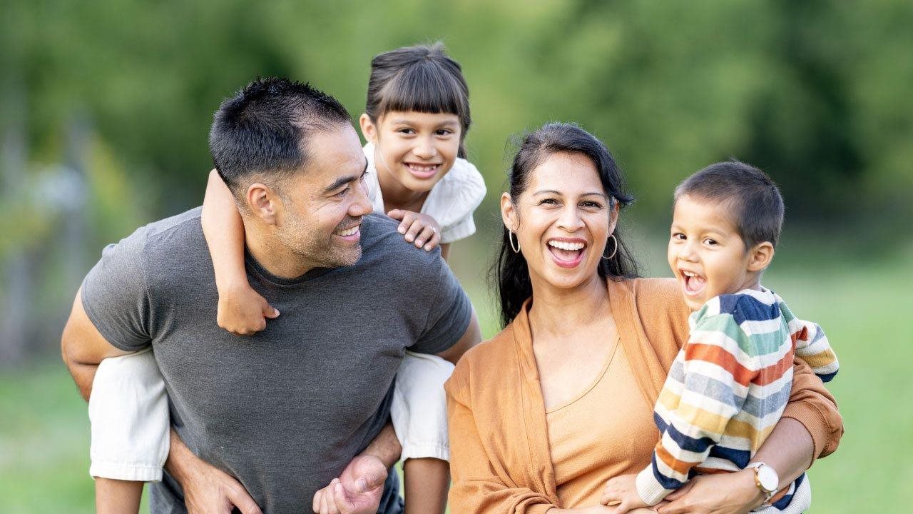 Happy young family playing in a park. Kemper Life provides free educational information about life insurance.