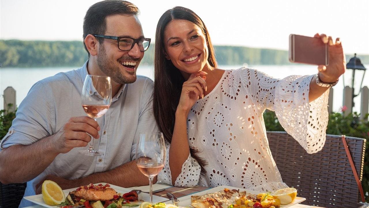 Couple taking a selfie while enjoying Chilean salmon in a restaurant.