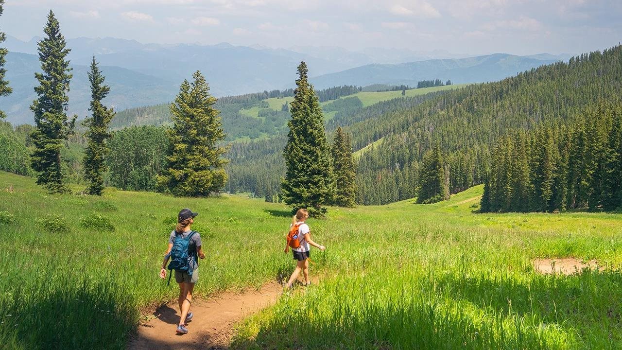 Two hikers enjoying the cool mountain vistas at the Beaver Creek Resort during the summer.