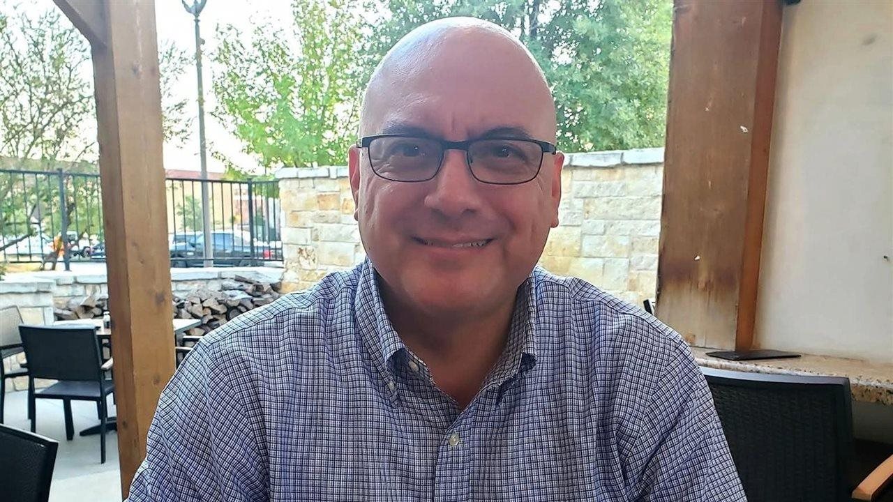 David R., residente de Austin, Texas, a quien en su momento le diagnosticaron insuficiencia renal en etapa 5, está sentado en una mesa al aire libre en un restaurante.