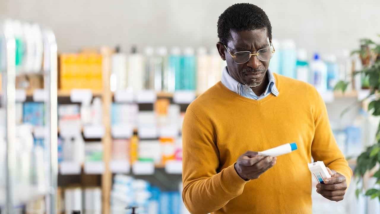 Man looking at a topical cream in a drug store.
