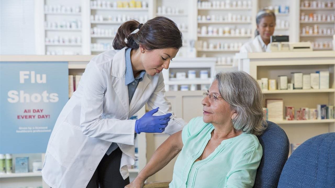 Older woman getting her flu shot from a pharmacy. Patients can walk into their local Walgreens or schedule an appointment online through Walgreens.com/ScheduleVaccine.
