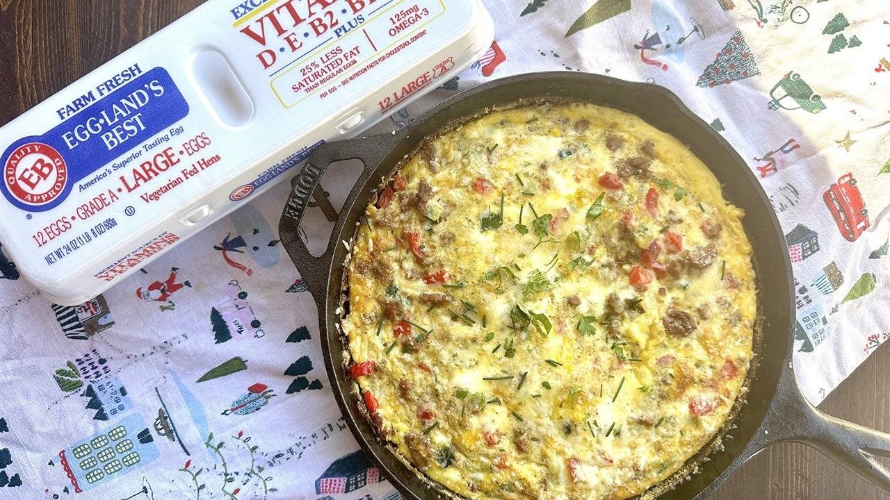 Vegetarian egg casserole in a skillet on a table next to a carton of Eggland's Best eggs.