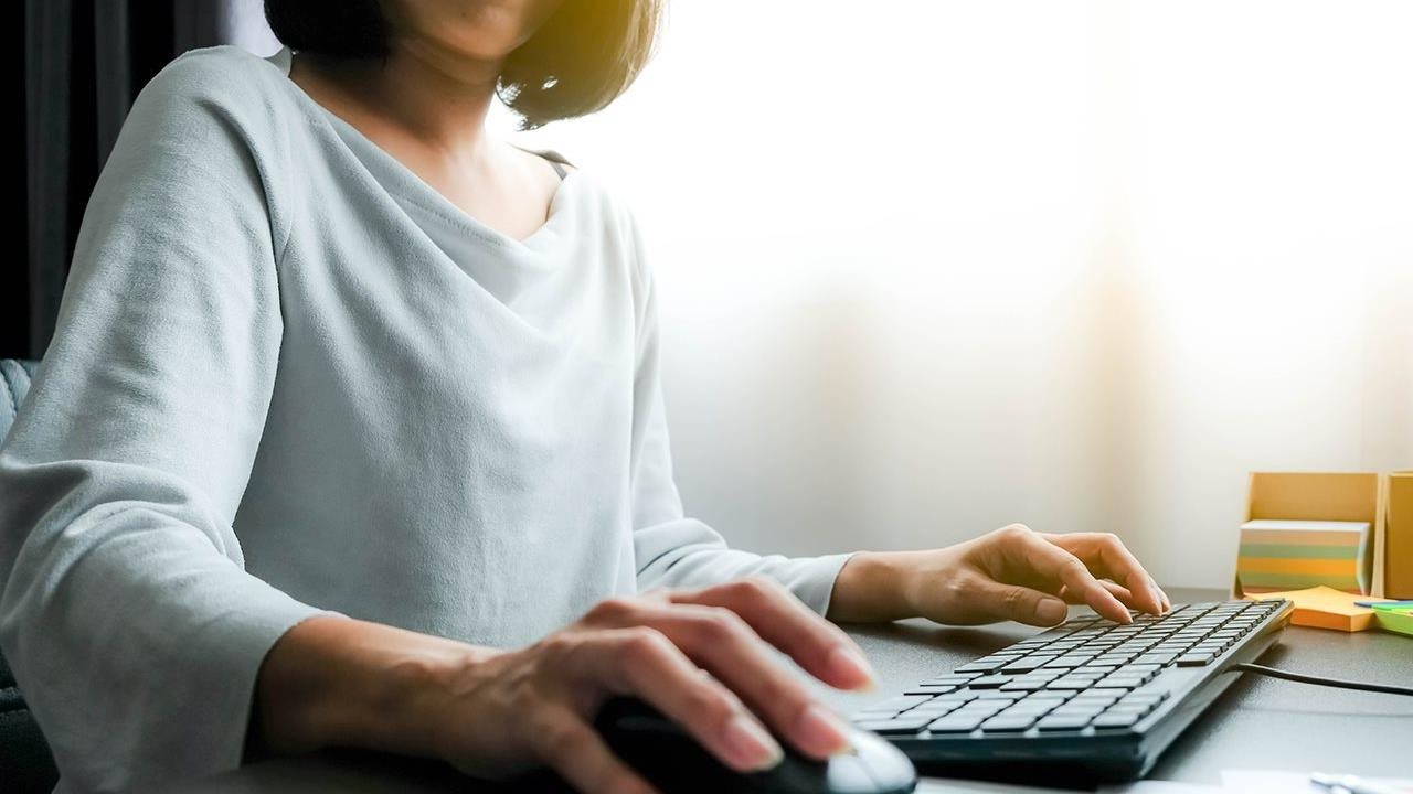 A customer on a laptop using her mouse to click-through to a web site and make a purchase.