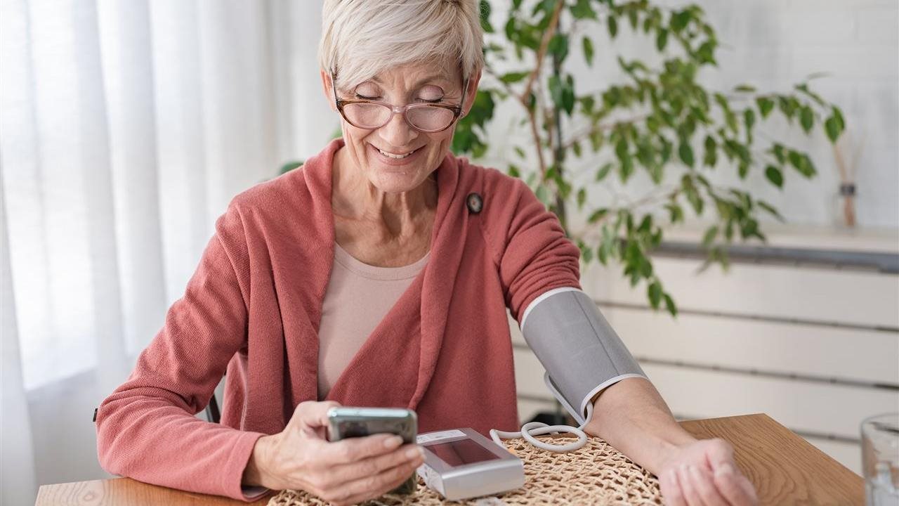 Senior woman takes blood pressure and uses phone app. Anthem Whole Health connects individual’s healthcare touchpoints.