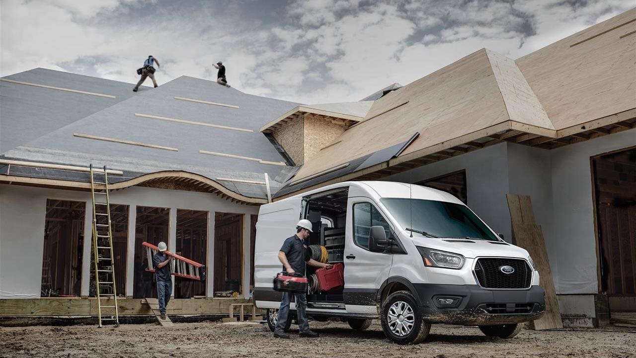 Construction worker unloading tools from his Ford Pro at a work site.