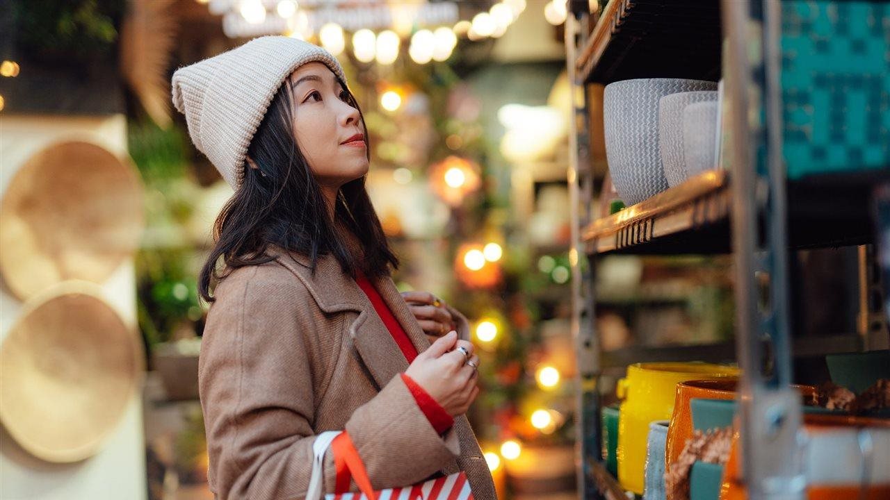 Woman, wearing a coat and winter hat, holiday shopping in a pottery store
