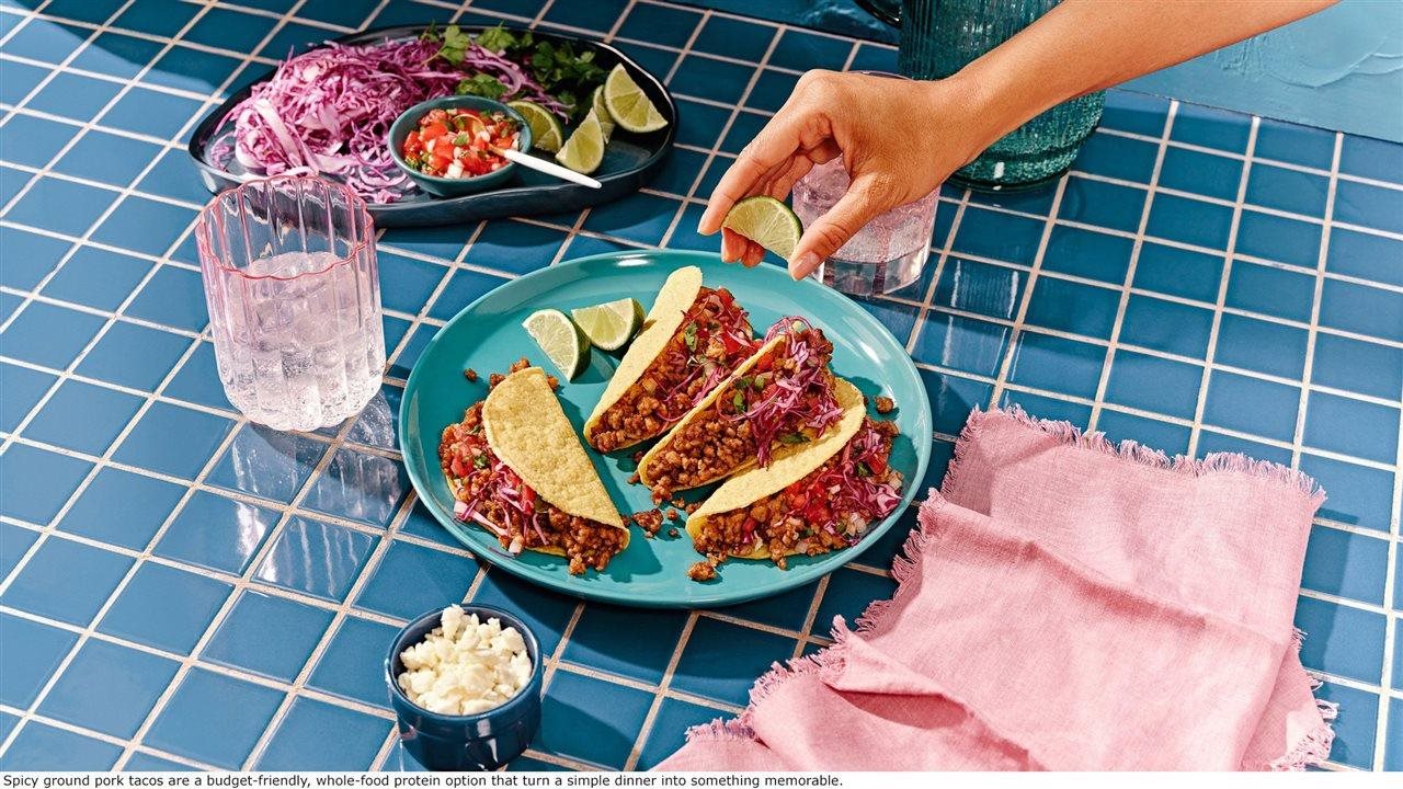 A woman seasoning a plate full of ground pork tacos with lime juice following a recipe she found on Taste What Pork Can Do.