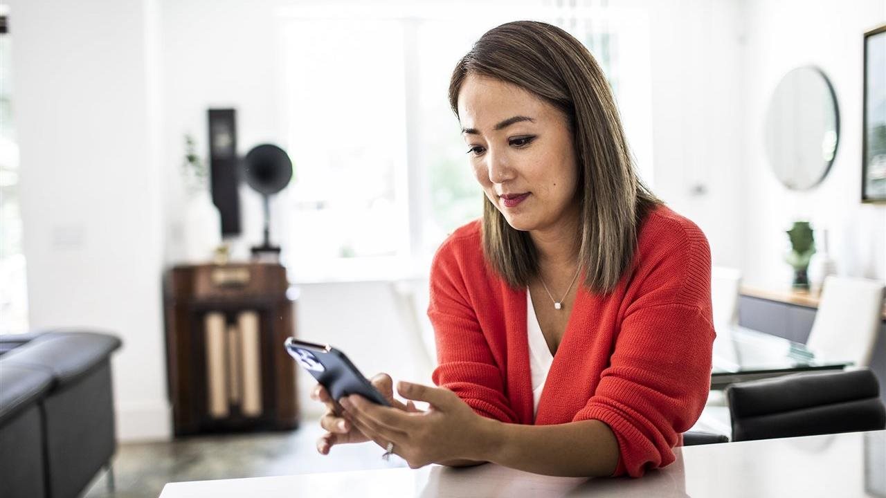 Woman using a phone app at home. With the Sydney Health app, members can find in-network care, see estimated costs and manage benefits in one place.