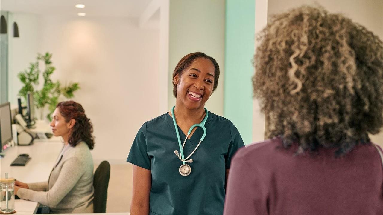 Health care worker greeting patient in lobby. One Medical's providers focus on building long-term relationships.