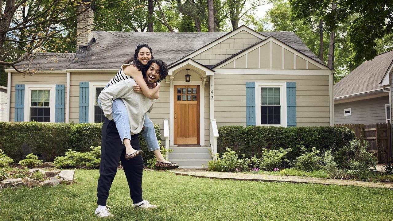 Happy young couple in the front yard of the home.