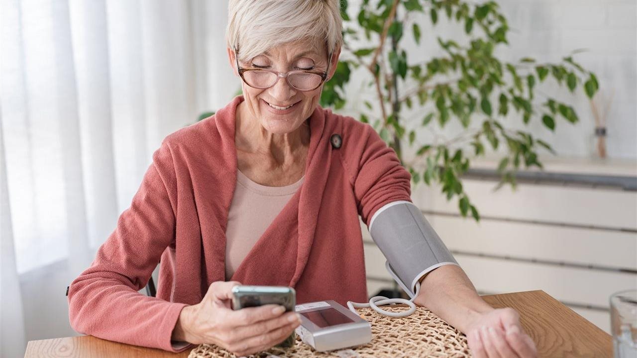 Senior woman takes blood pressure and uses phone app. Anthem Whole Health connects individual’s healthcare touchpoints.