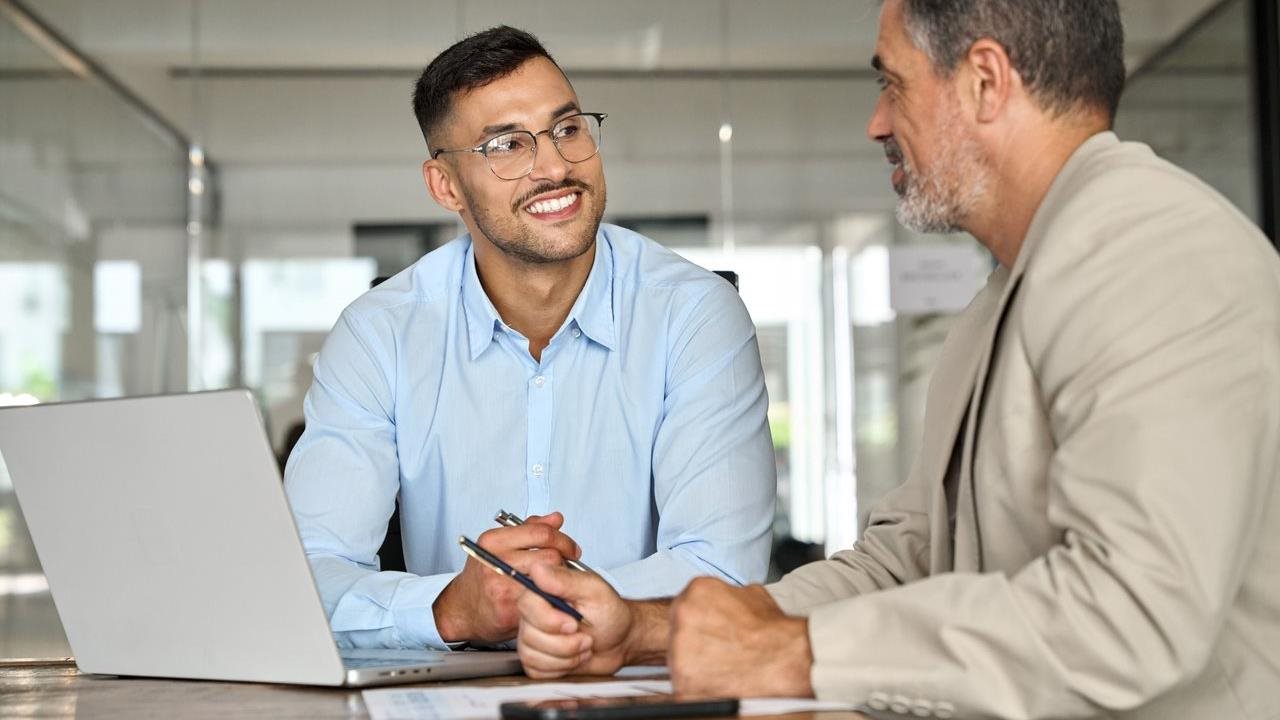 Two professionals using a laptop and using Agentic AI to unlock the valuable insights hidden in data.