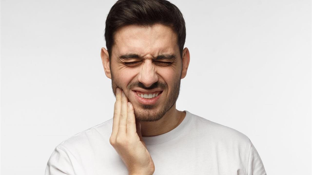 Man with beard and mustache experiencing painful mouth due to tooth grinding.