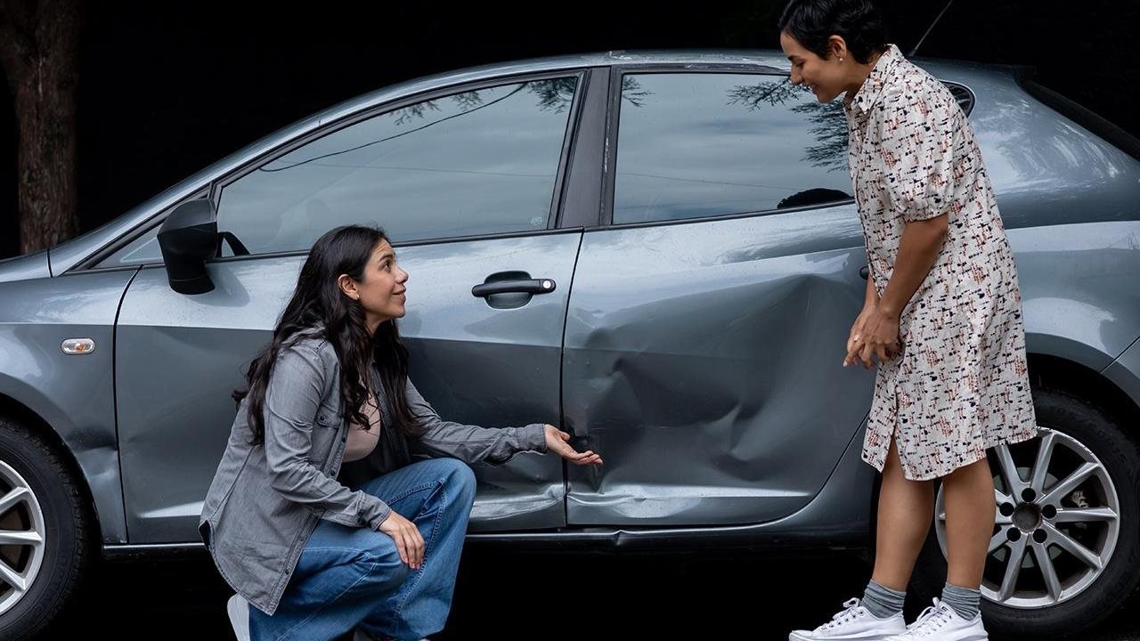 Two women assessing the damage to a car involved in an accident.