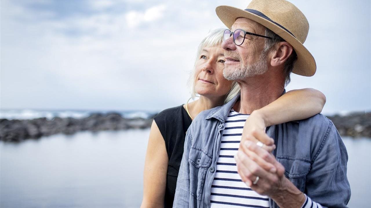 Senior couple hugs while on a dock by the lake. Merck is conducting a clinical trial for NSCLC.