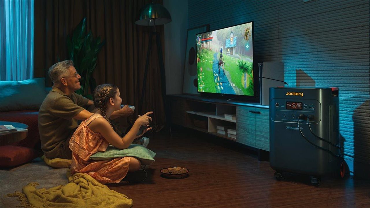 Grandfather and granddaughter playing a video game powered by a Jackery generator.