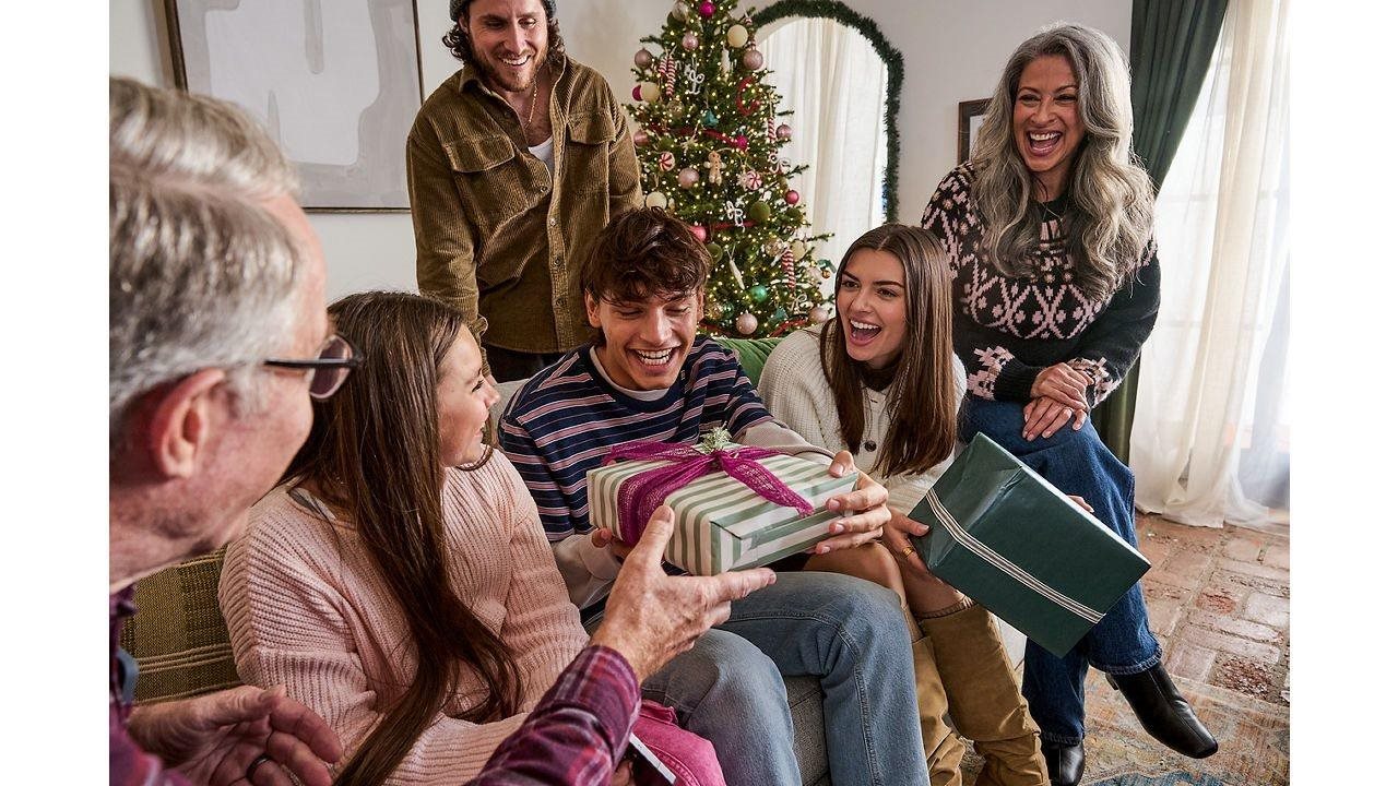 Familia feliz intercambiando regalos en la sala de estar con un árbol de fondo.
