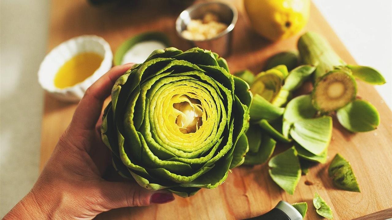 Cut and clean artichoke above cutting board with sauce dish in the background. Quality artichokes come from Ocean Mist Farms.