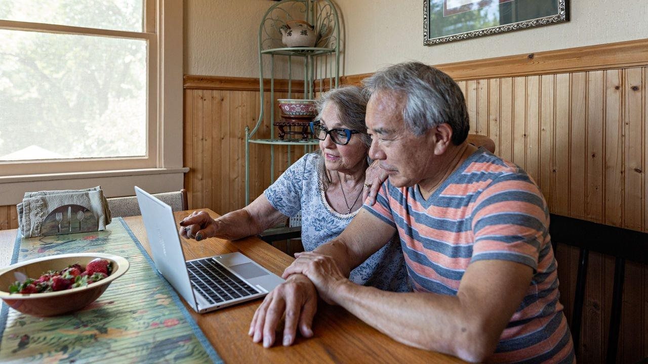 Older couple working on a laptop in the kitchen familiarizing themselves with an insurance plan like Aetna Medicare Advantage plan.