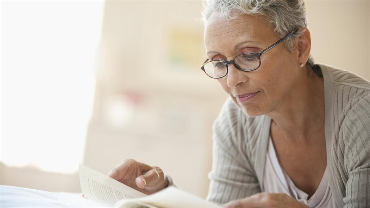 Woman wearing glasses reading a book.