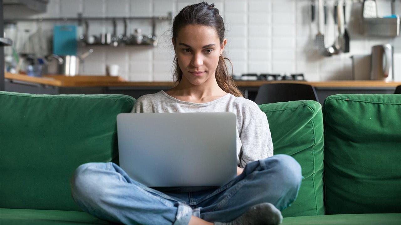 Young woman sitting on sofa at home using a laptop.